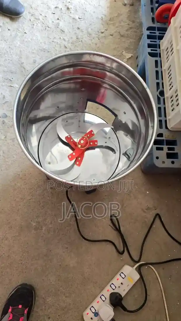 A top-down view of an electric stainless steel fodder cutter with sharp rotating blades, used for processing animal feed in a farming environment.