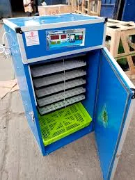 A blue industrial egg incubator with an open door, revealing multiple tiers of white egg trays and a green tray at the bottom.
